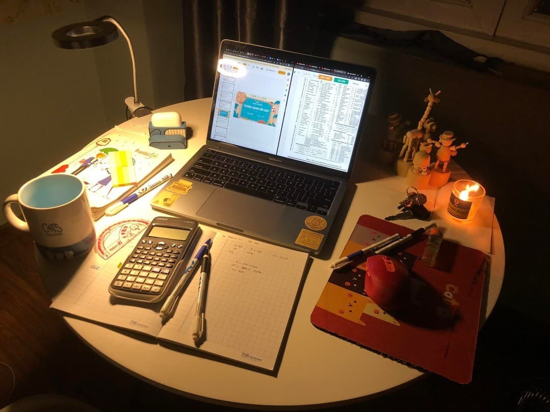 Duy’s desk with a laptop, notebook, and candle